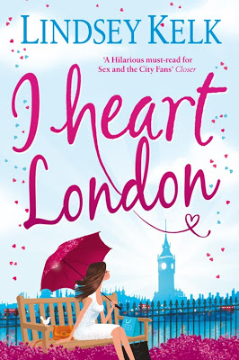 The cover of "I Heart London by Lindsey Kelk" features a woman sitting on a bench, holding a pink umbrella and gazing at the iconic Big Ben clock tower. The title, written in large, playful script with pink heart accents, stands out against a backdrop adorned with delicate pink floral designs.