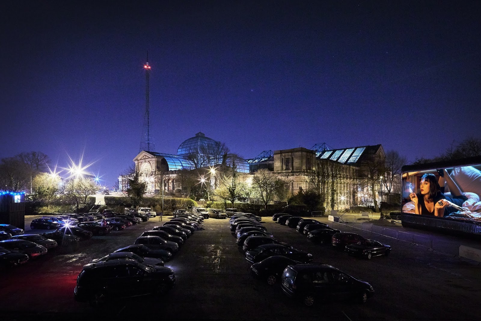 A drive-in film club in London. You can see cars parked up with Alexandra Palace in the background, and a big screen broadcasting Pulp Fiction.