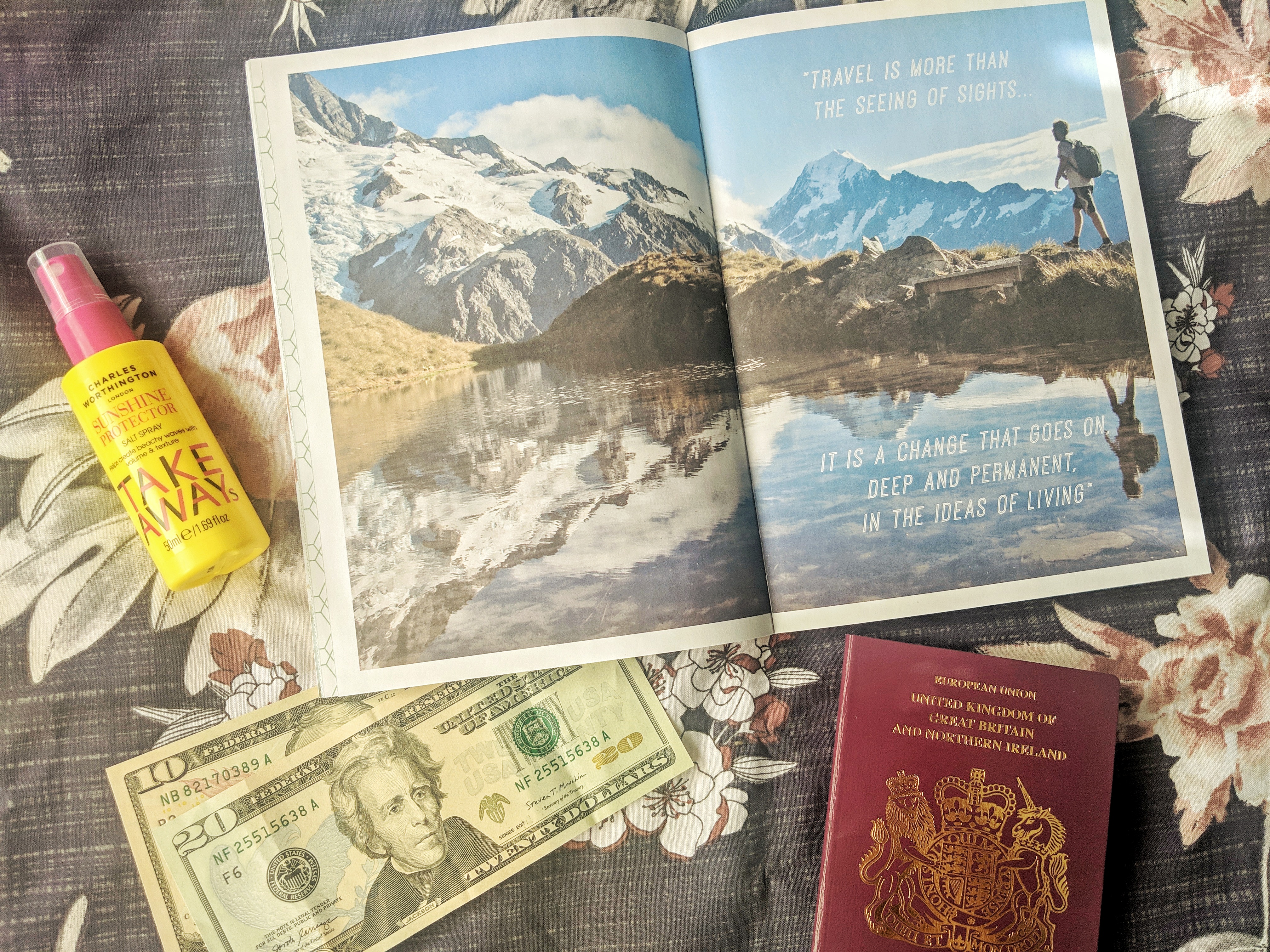 A flat lay of travel related objects on my bed. As well as my passport, there is some american dollars, a small yellow bottle of hair spray/protector and a small travel book opened on a huge photo of some snowy mountains. The quote on the page reads 'travel is more than the seeing of sights. It is a change that goes on deep and permanent, in the ideas of living'. Louise is using this book to plan her upcoming trip to America.